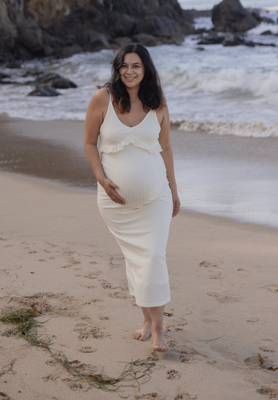 Norma Barrios smiling in a white dress on the beach
